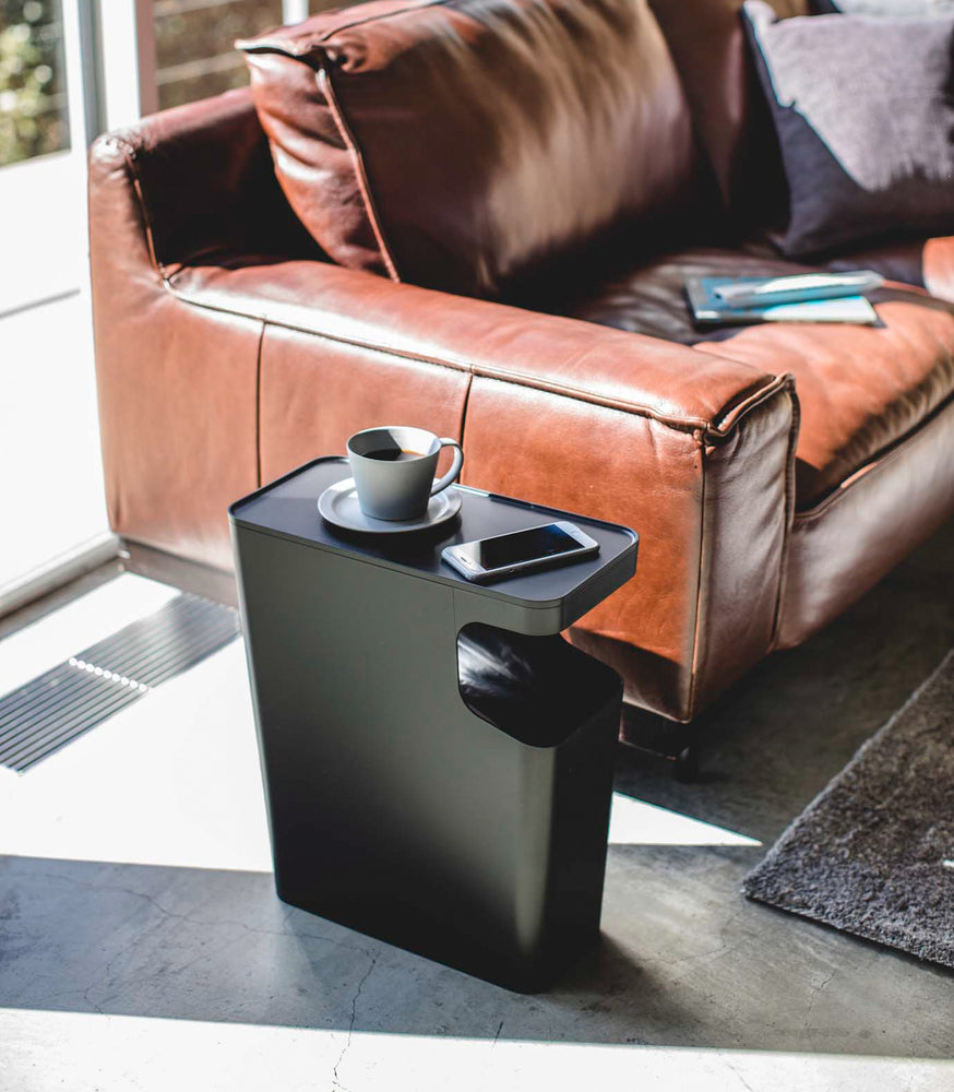 View 8 - Black Side Table Trash Can displaying cup and phone in living room by Yamazaki Home.