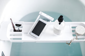 Aerial view of white Expandable Bathtub Caddy holding phone and beauty products by Yamazaki Home. view 4