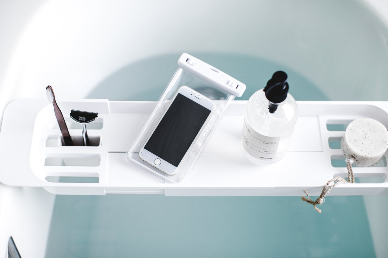 View 4 - Aerial view of white Expandable Bathtub Caddy holding phone and beauty products by Yamazaki Home.