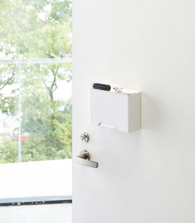 White Face Mask Dispenser holding keys on door by Yamazaki Home. view 3