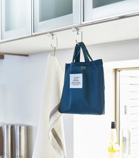 White Undershelf Hangers in kitchen holding towel and bag by Yamazaki Home. view 5