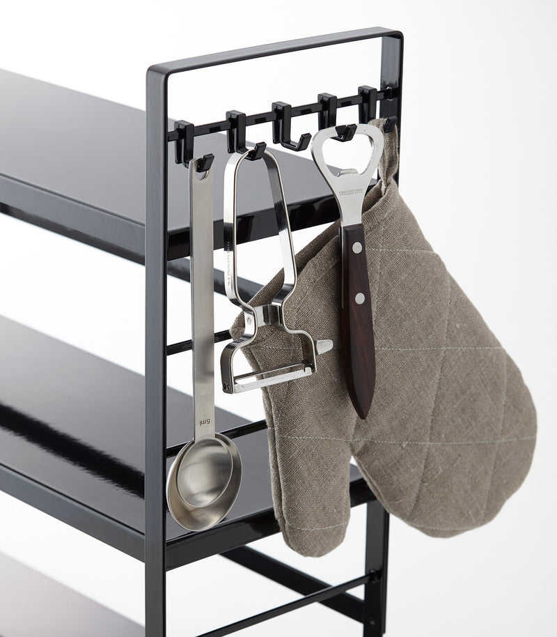 Side view of black Countertop Organizer displaying kitchen cooking accessories on white background by Yamazaki Home.